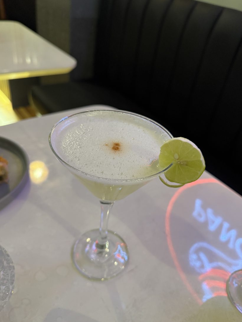Pisco sour de Panchita servido junto al neón rojo del local